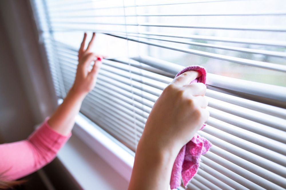 Woman Hands Cleaning Blinds Using a Cloth — Window Furnishing Services in Tweed Heads, NSW