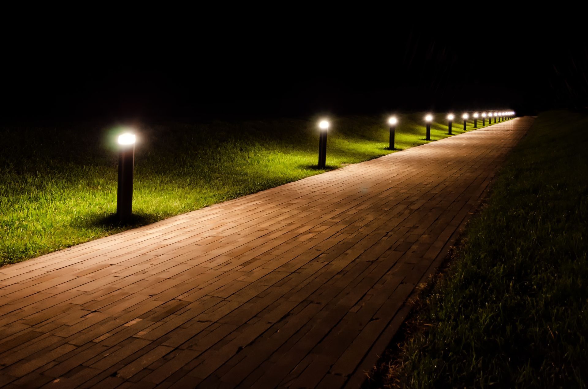 A wooden path with lights on the side of it at night.