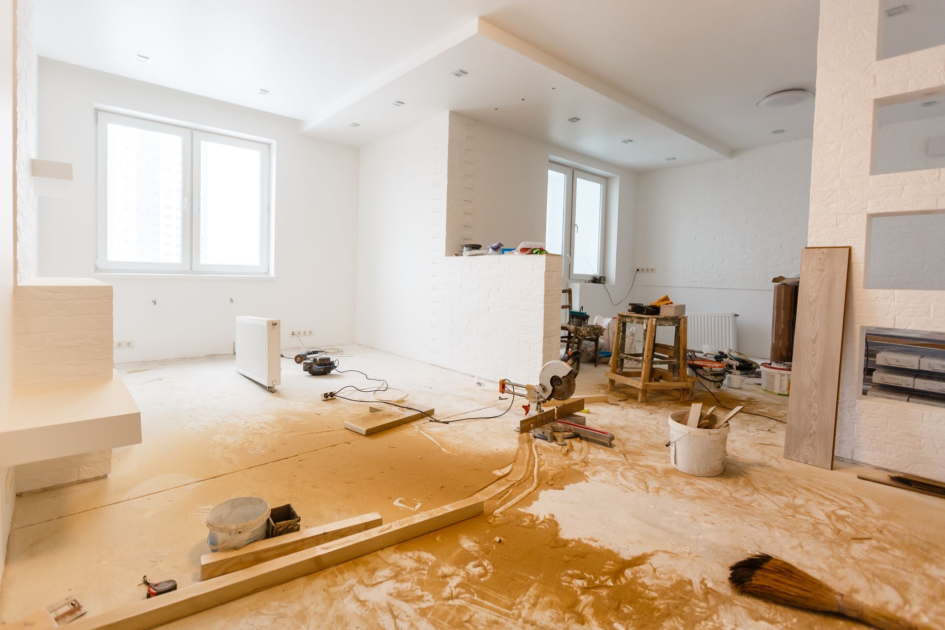 A living room under construction with a lot of tools on the floor.