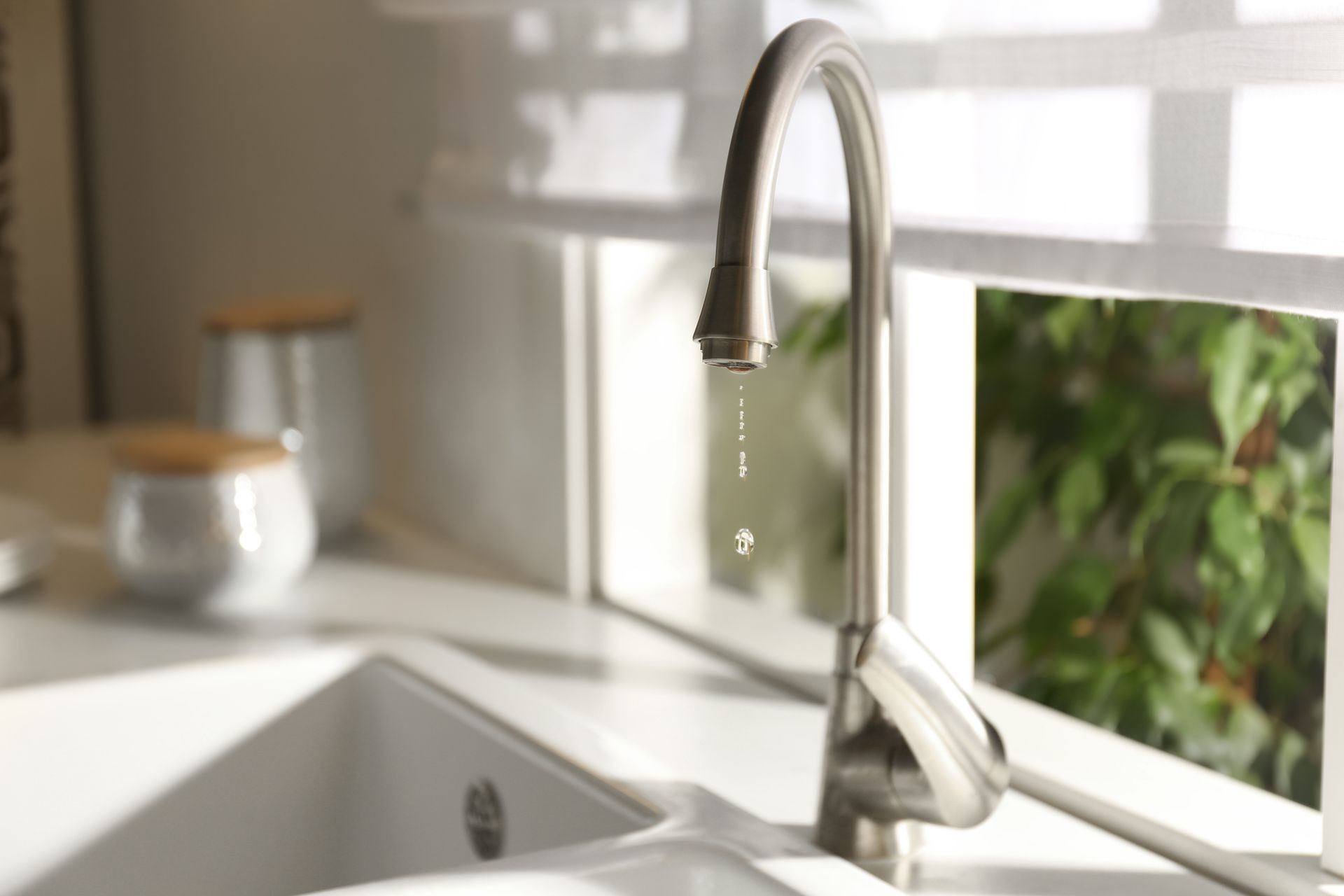 A kitchen sink with a faucet running and water dripping from it