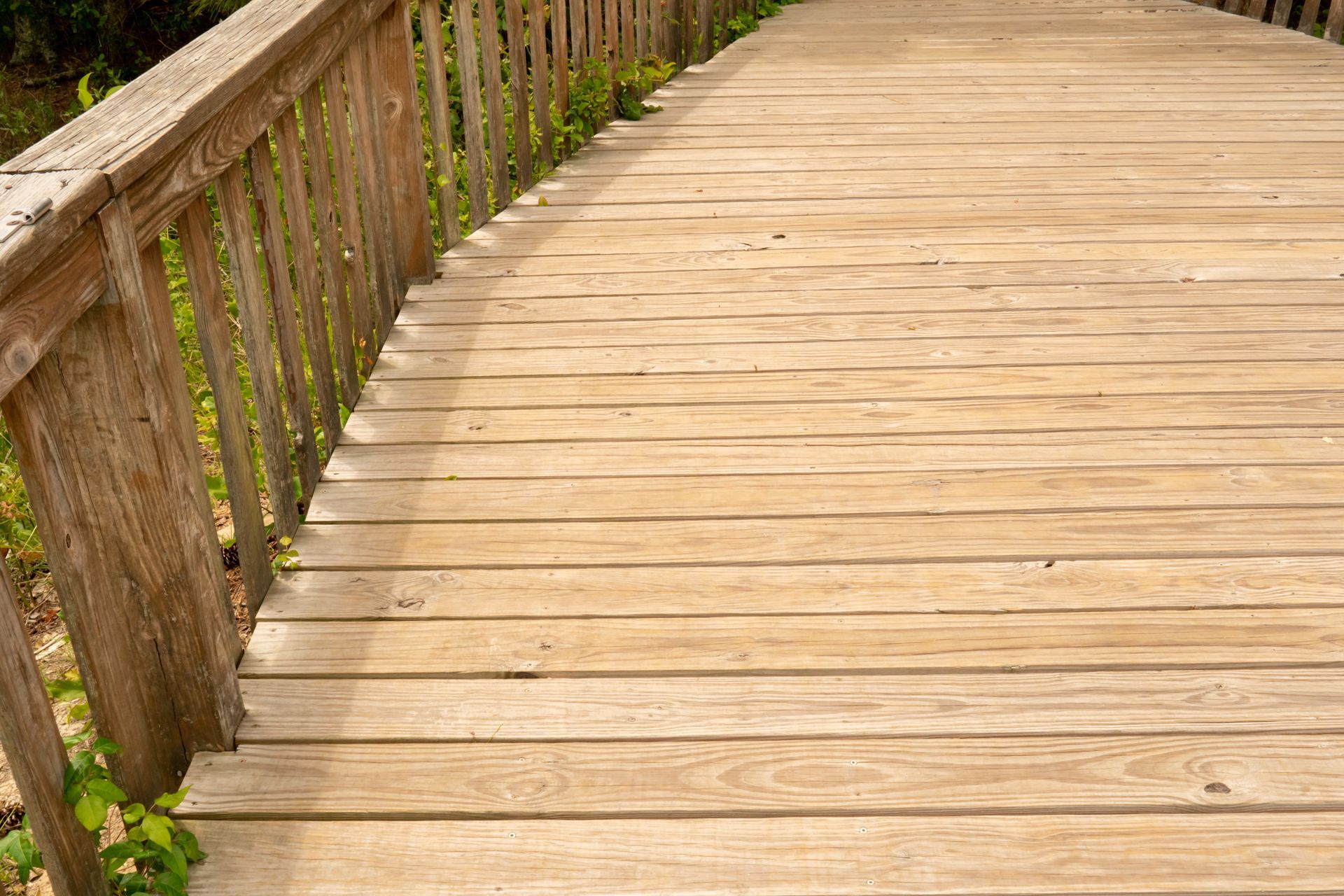 A wooden bridge with a wooden railing going over a river.