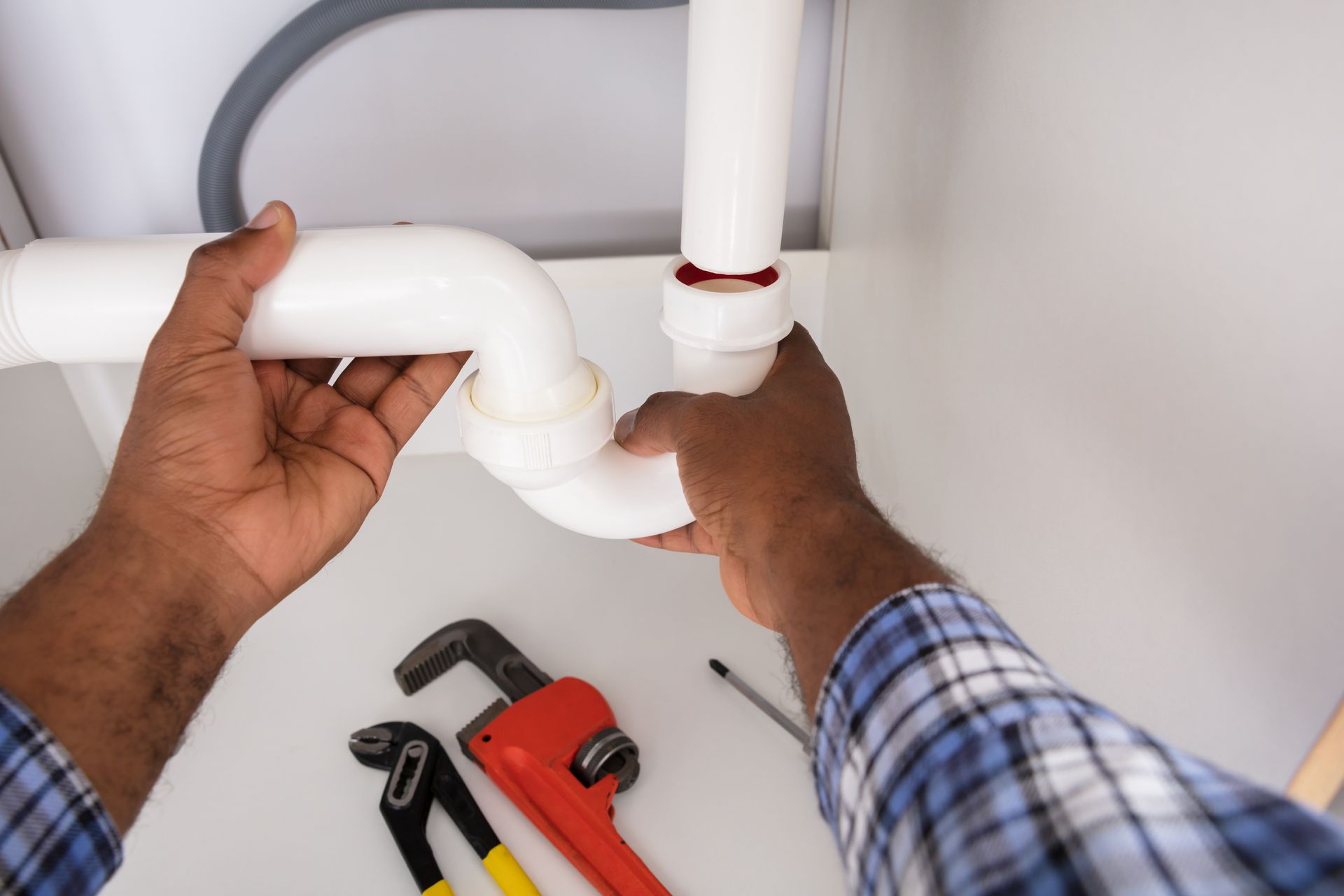 A plumber is fixing a pipe under a sink.