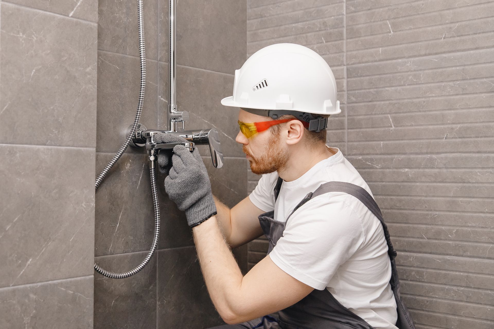 A man is fixing a shower head in a bathroom.