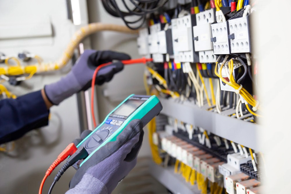 An electrician is using a multimeter to test a circuit board.