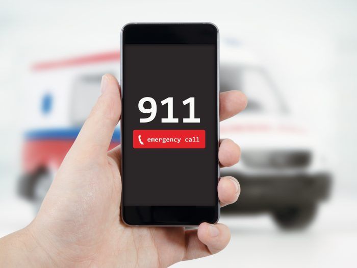 A person is holding a cell phone with the number 911 on it.