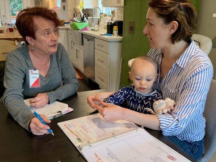 Two women are sitting at a table with a baby.