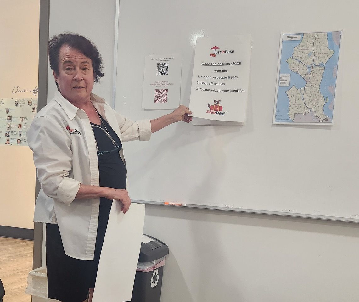 A woman is standing in front of a whiteboard holding a piece of paper.