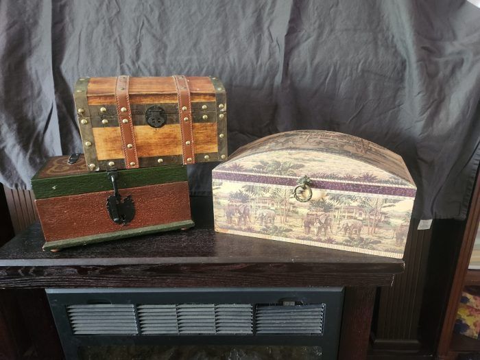 Three trunks are sitting on a table next to a fireplace.