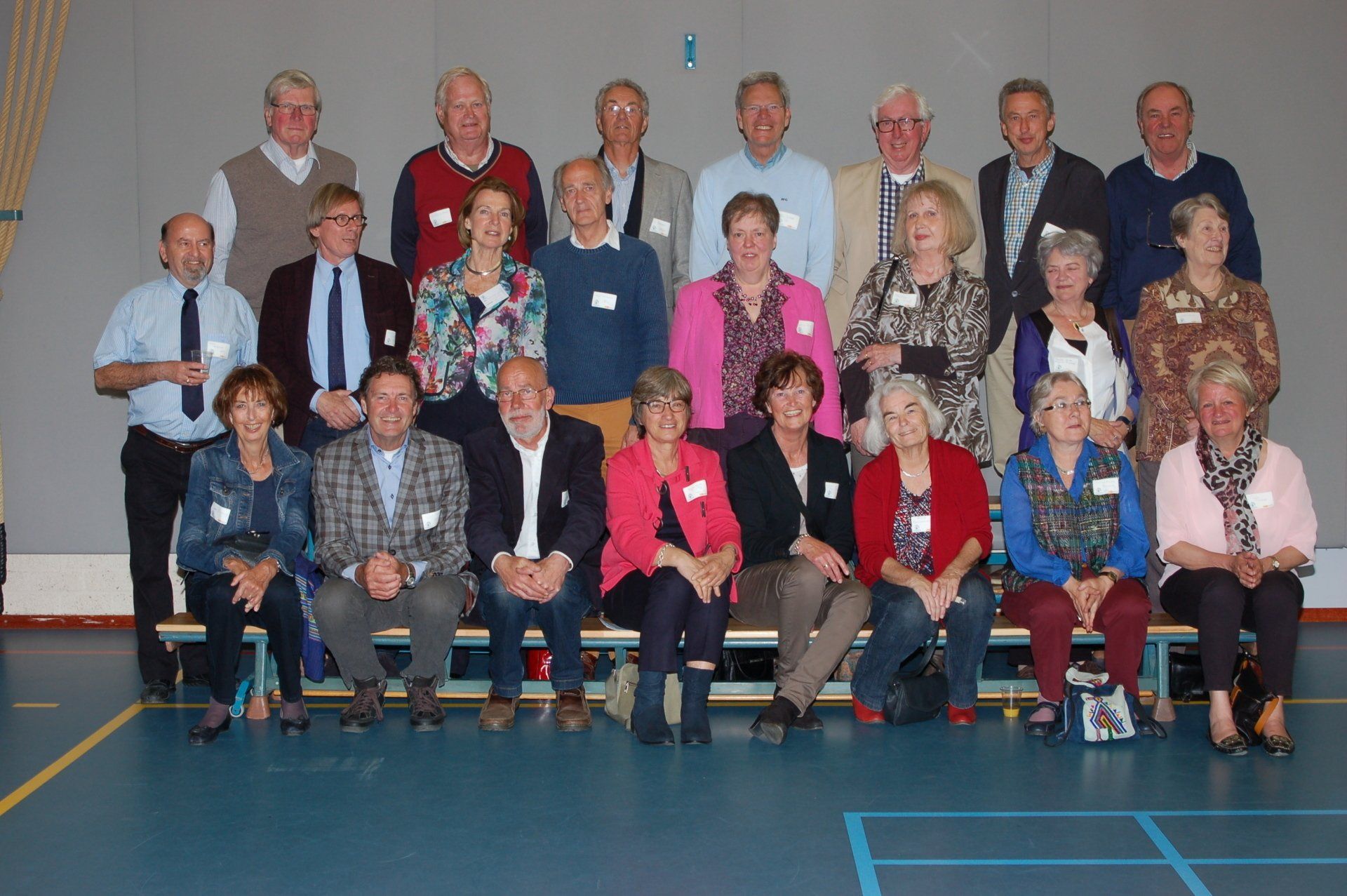 Groepsfoto van een lachende bejaarde in een gymzaal.
