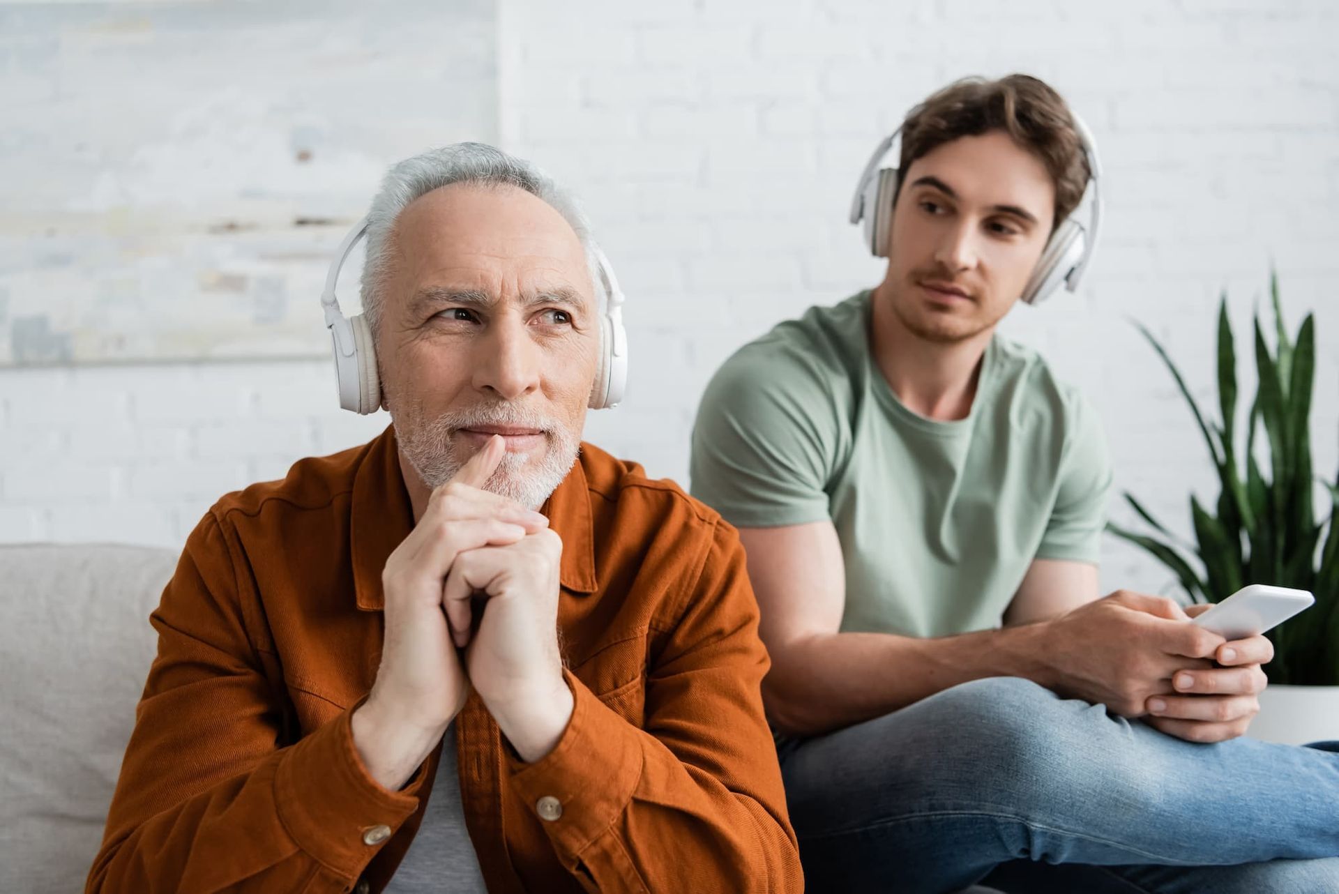 image of a younger man and elder man testing out their hearing using headphones