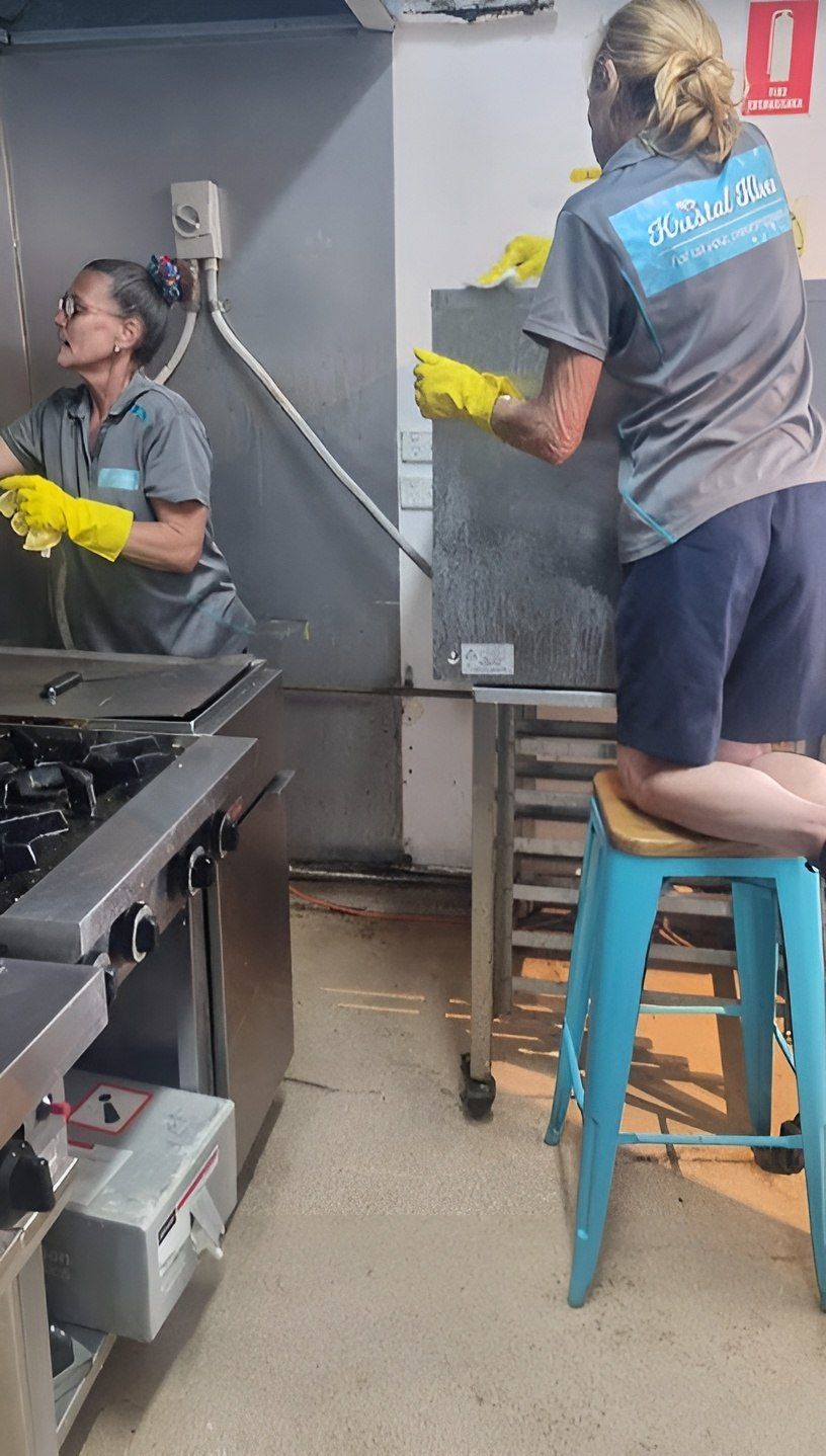 Two Women Are Cleaning a Refrigerator in a Kitchen — Kristal Kleen Services in Jubilee Pocket, QLD