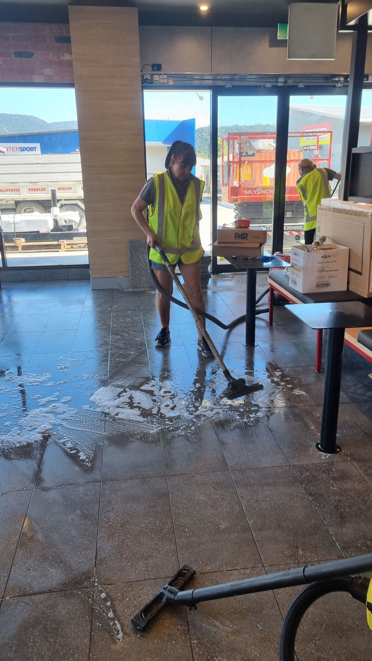 A Woman Is Cleaning An Office With A Vacuum Cleaner — Kristal Kleen Services in Jubilee Pocket, QLD