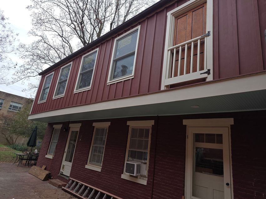 Maroon two-story building with white trim and a covered lower walkway, viewed from outside
