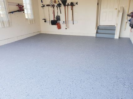 Garage with a speckled gray epoxy floor and tools hanging on the wall.