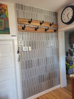 Entryway wall with gray patterned wallpaper, wooden coat rack, and wall clock beside a doorway