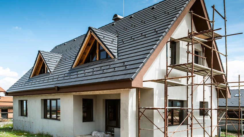 New house under construction with scaffolding and a dark gray roof