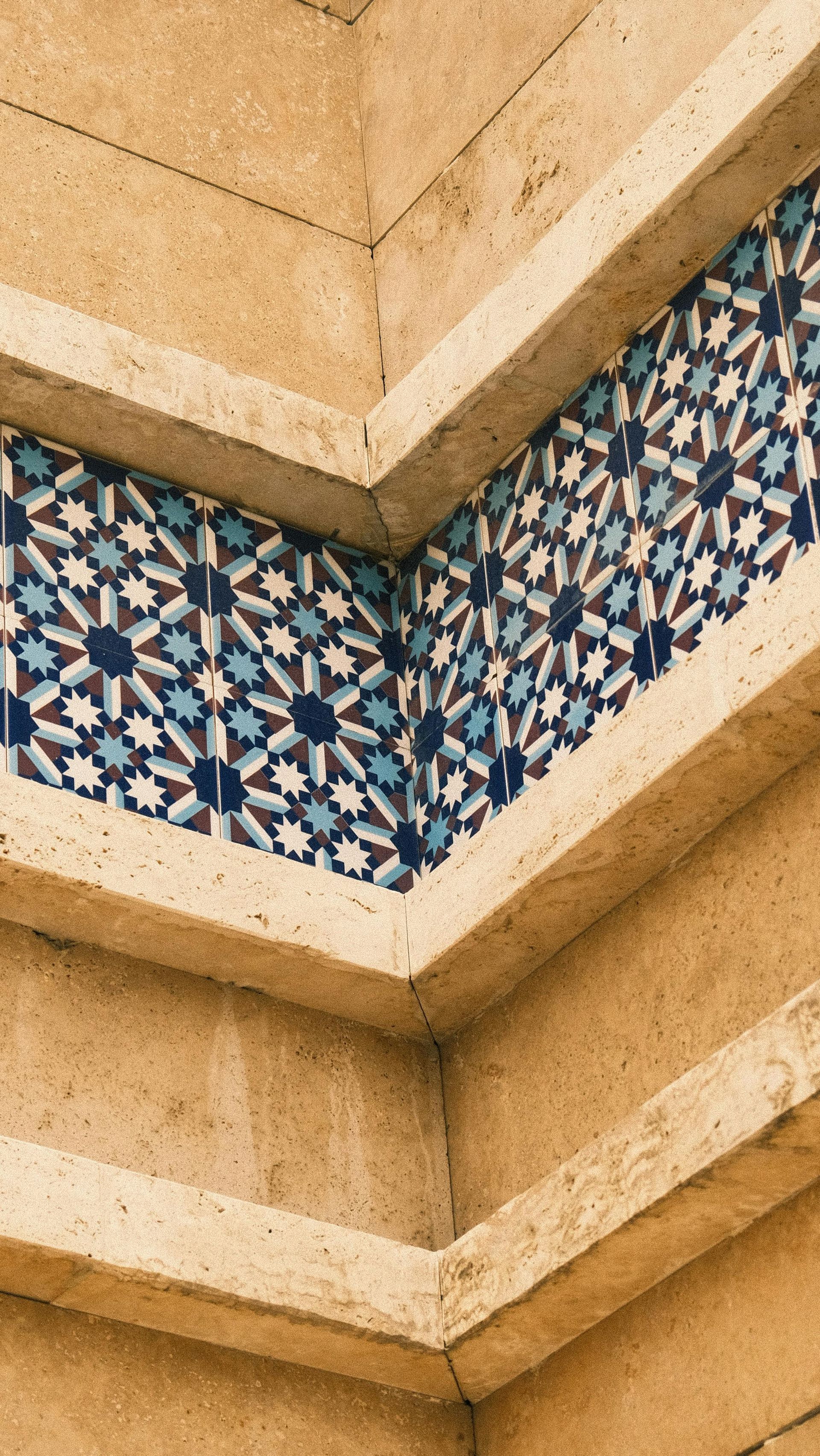 Geometric blue-and-white mosaic band on a beige stone building corner