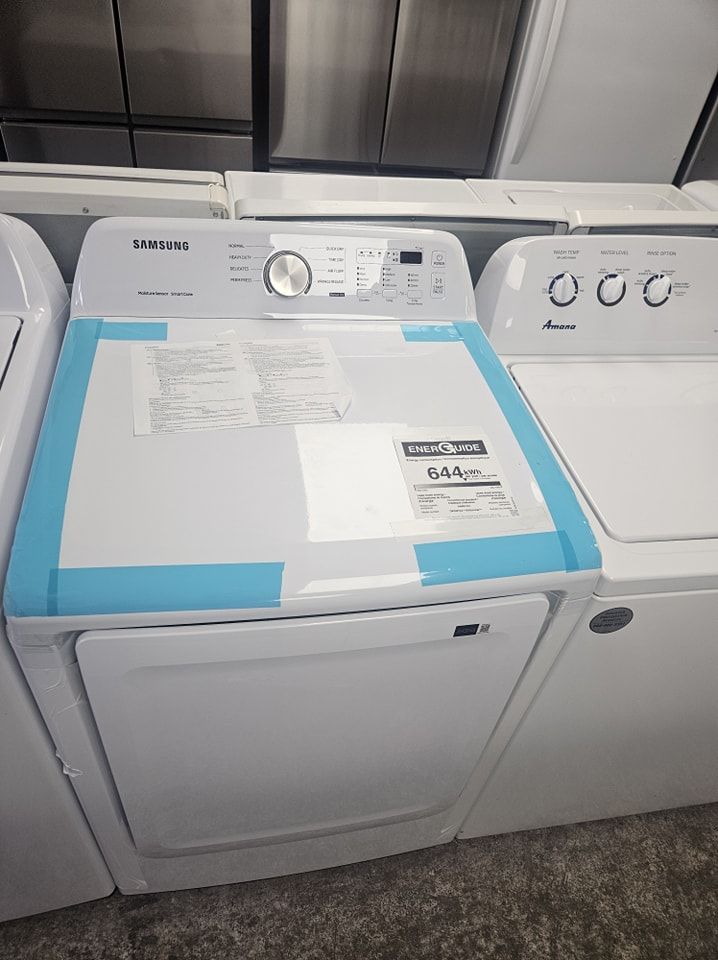 Appareils de lavage à chargement frontal avec une machine à laver blanche au centre, un couvercle recouvert de ruban adhésif bleu et un sèche-linge à droite.