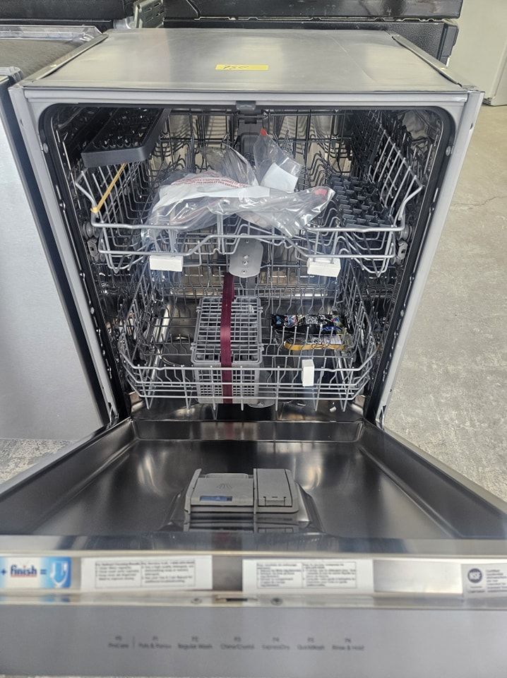 Lave-vaisselle ouvert avec des paniers métalliques et un sac en plastique à l'intérieur dans un cadre de cuisine