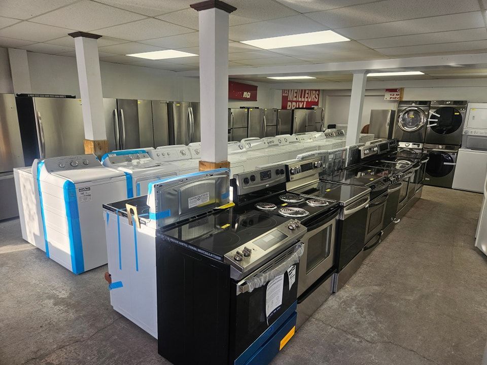 Salle d'exposition d'électroménagers : réfrigérateurs, cuisinières, lave-linge et sèche-linge exposés. Nombreux modèles disponibles à la vente.