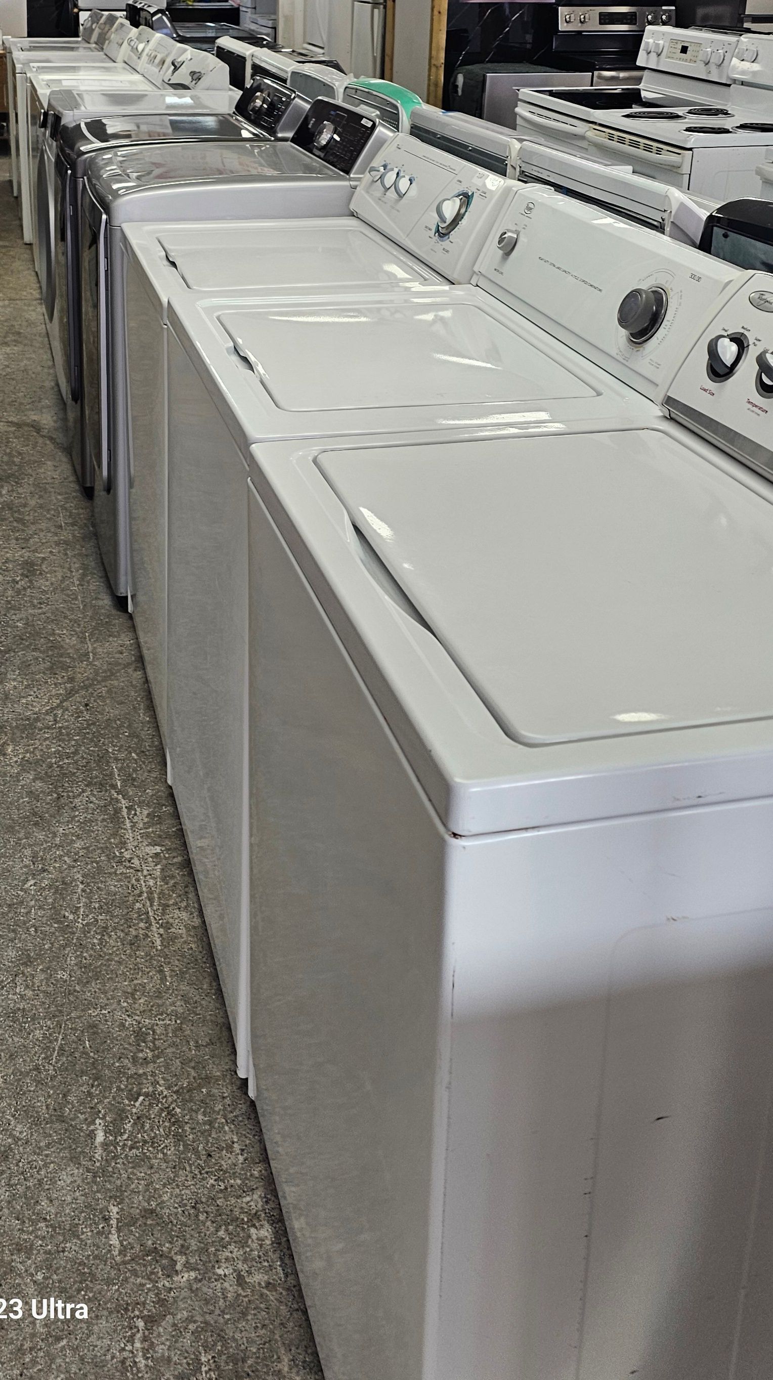 Rangée de machines à laver blanches dans un magasin, vue de biais.