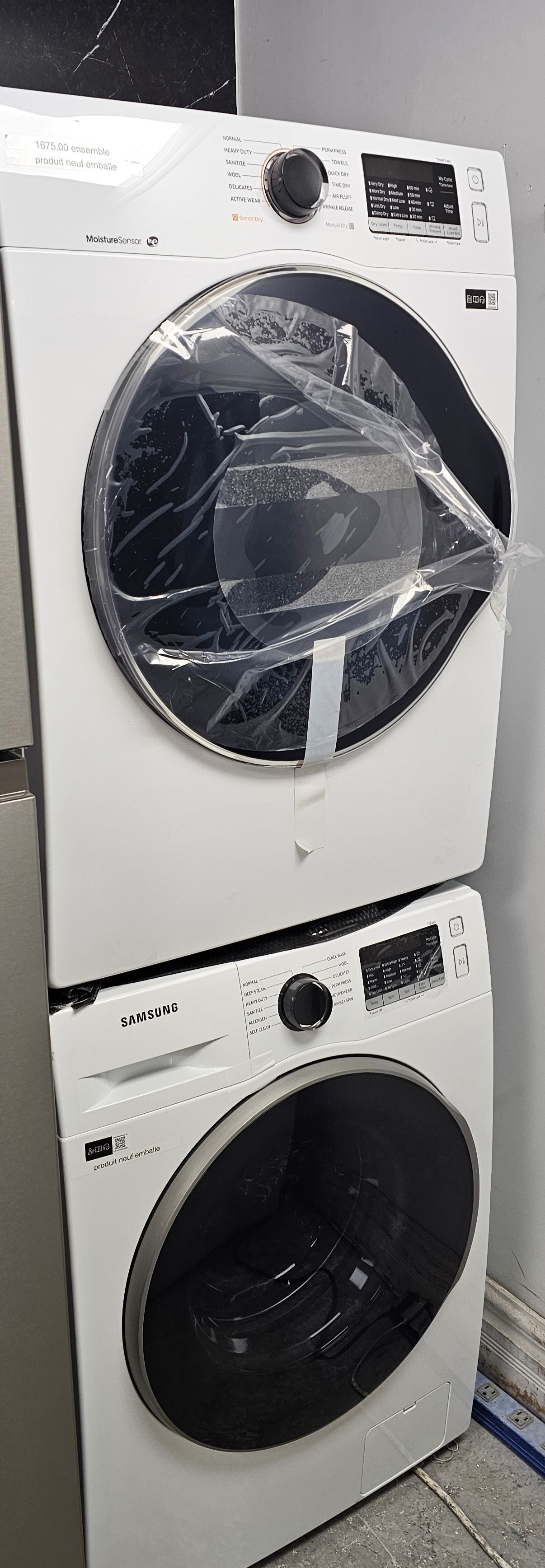 Lave-linge et sèche-linge blancs superposés, avec une protection en plastique transparent sur l'unité supérieure.