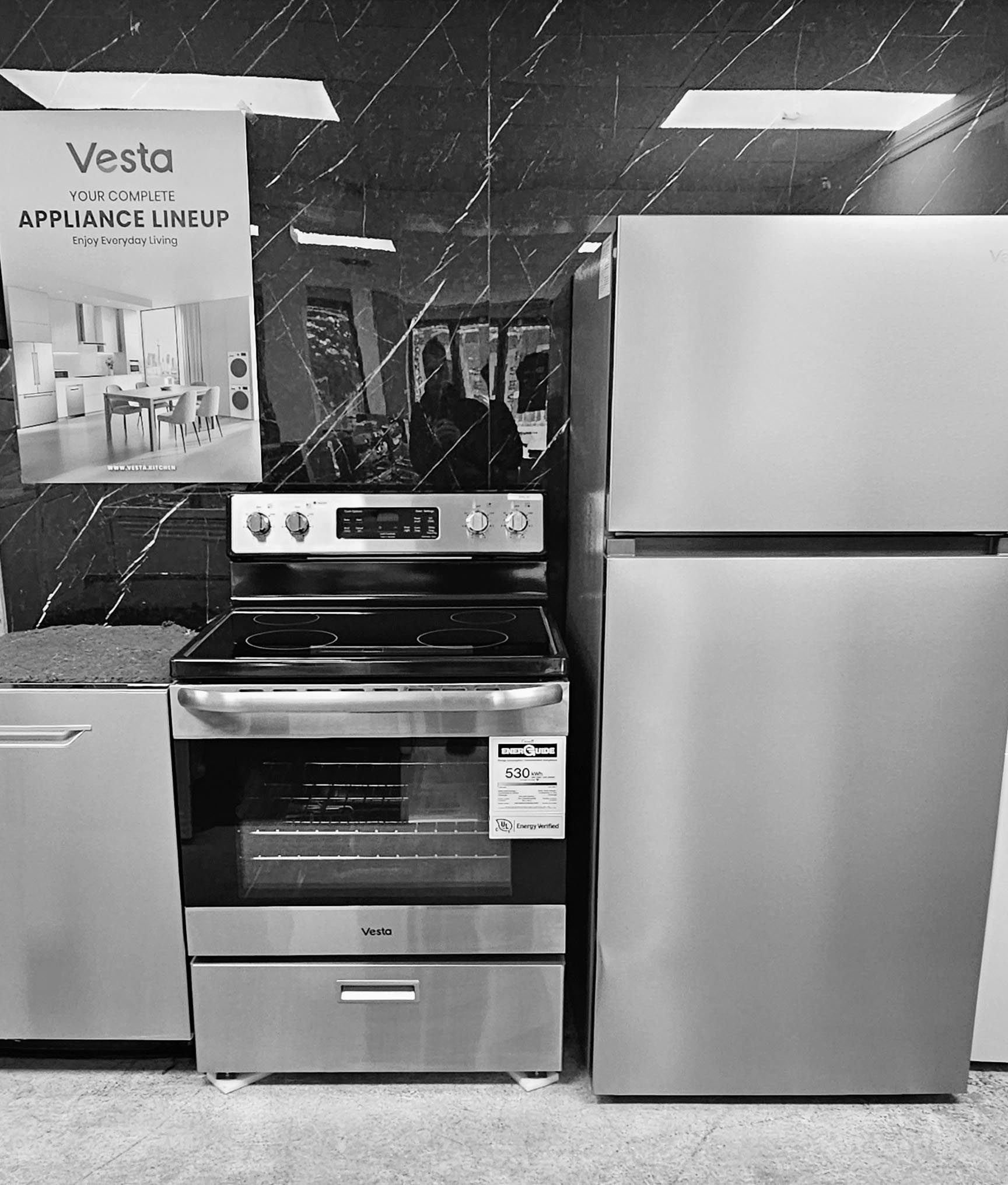 Cuisine d'exposition en noir et blanc avec cuisinière et réfrigérateur dans un magasin d'électroménager.