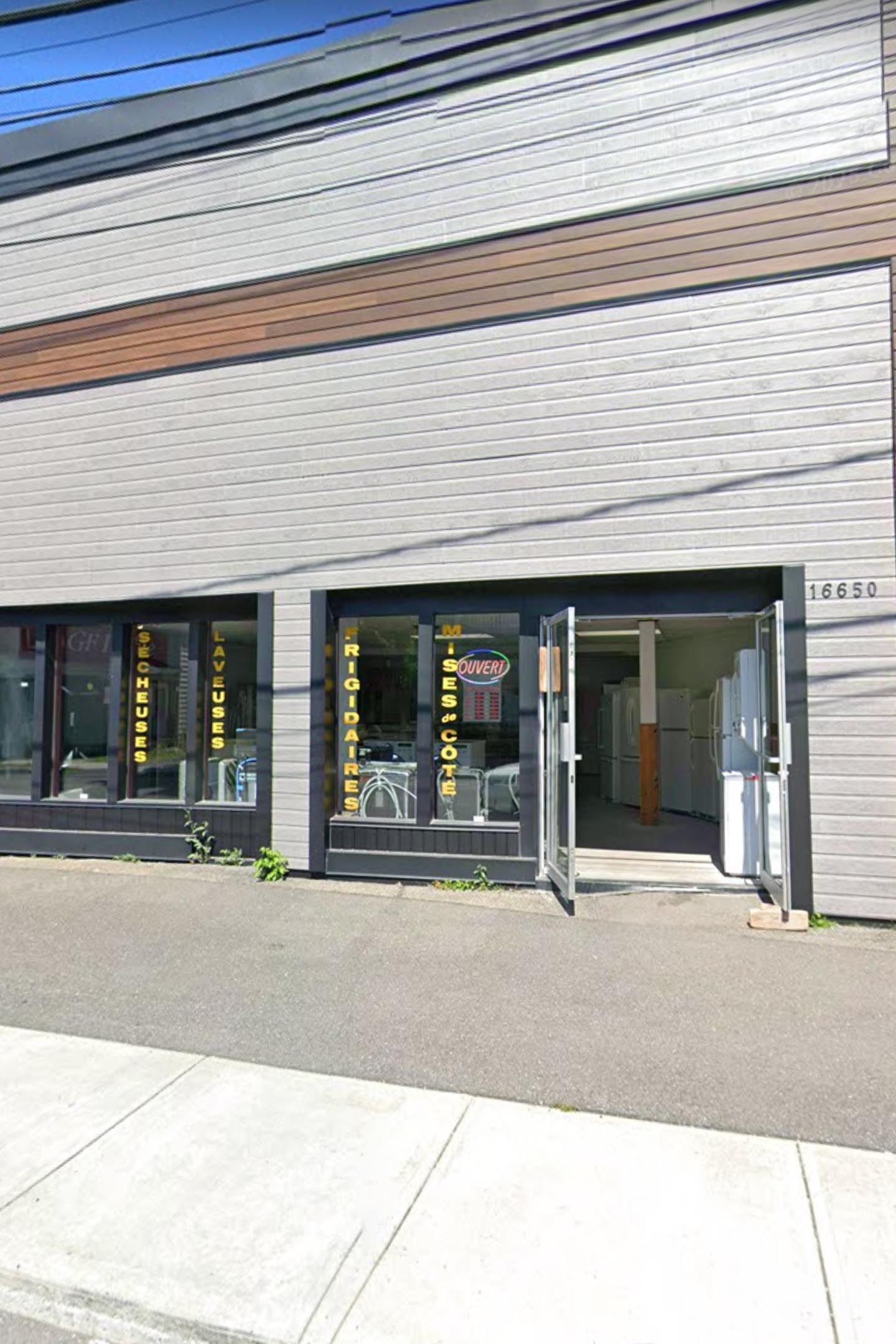 Façade vitrée avec porte ouverte. Le magasin possède une enseigne et semble vendre des articles.