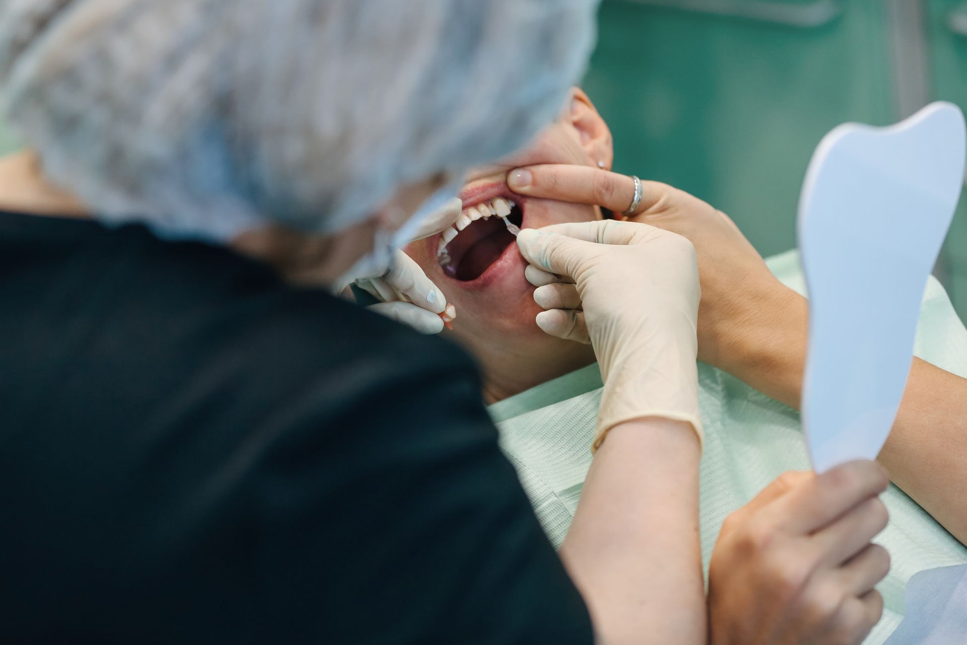 Dentist wearing protective gloves examining patient teeth for implants. Dentist wearing protective gloves examining patient teeth for implants.