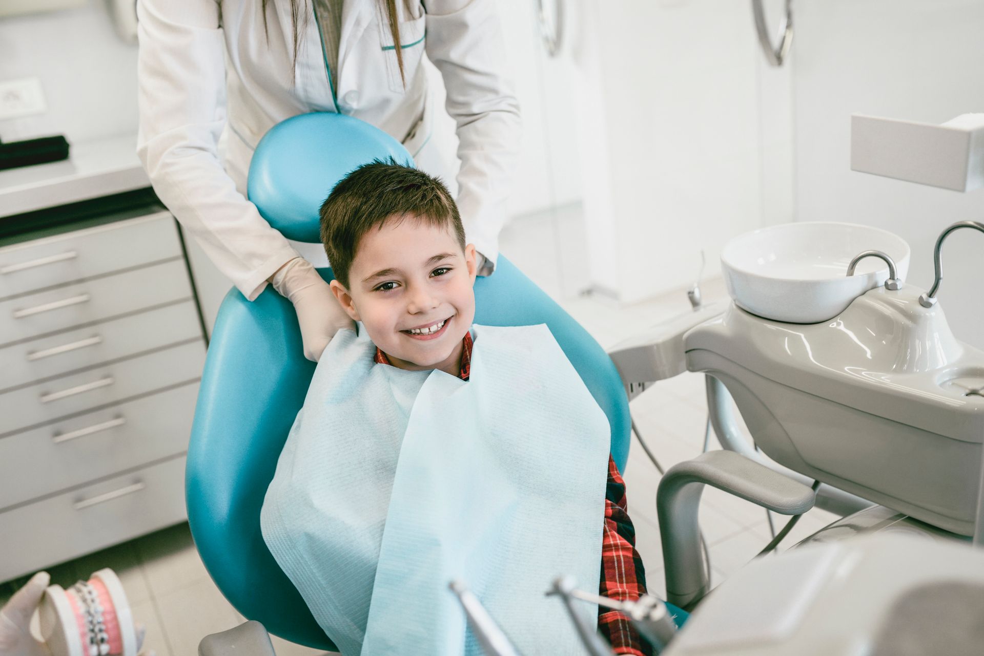 A young boy is sitting in a dental chair with a dentist.