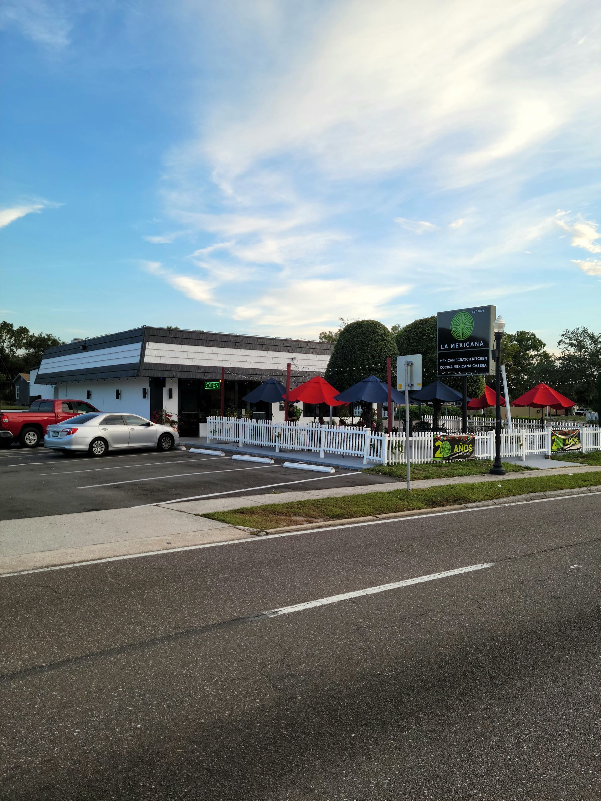A white car is parked in front of a restaurant