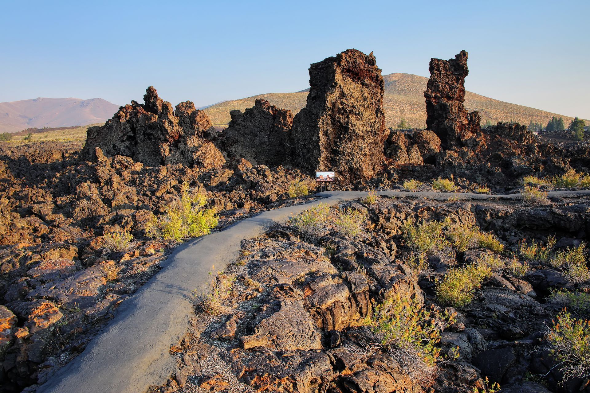 A road going through a rocky area with mountains in the background