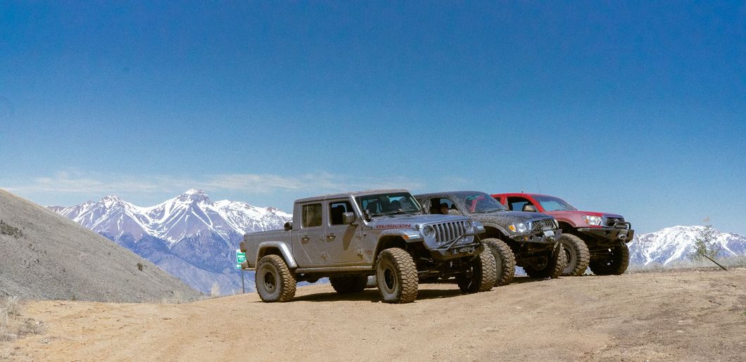 Three jeep 's are parked on top of a dirt hill.