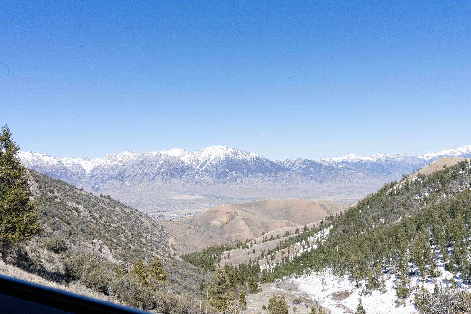 A view of a snowy mountain range from a car window.