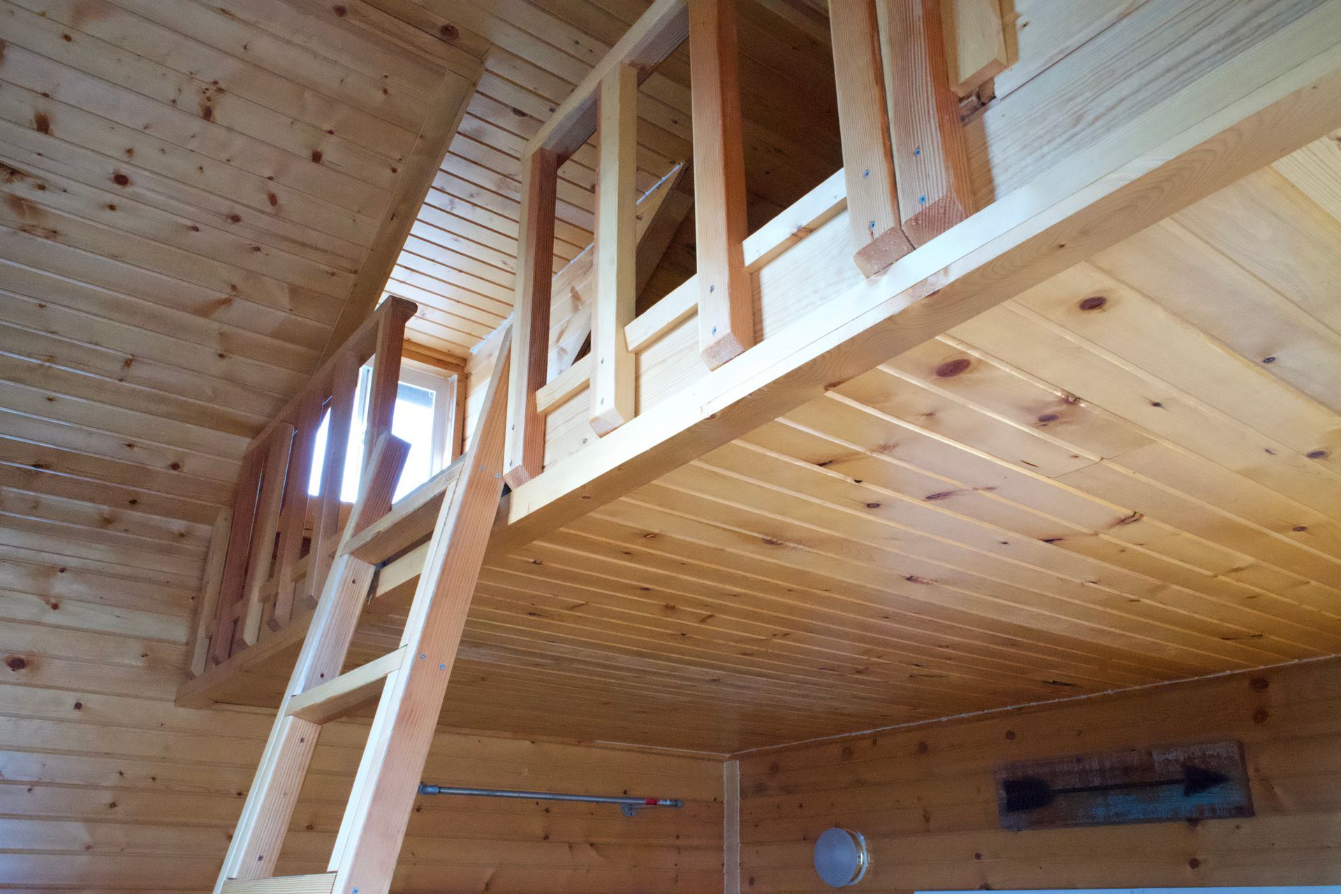 A wooden cabin with a ladder leading up to the second floor