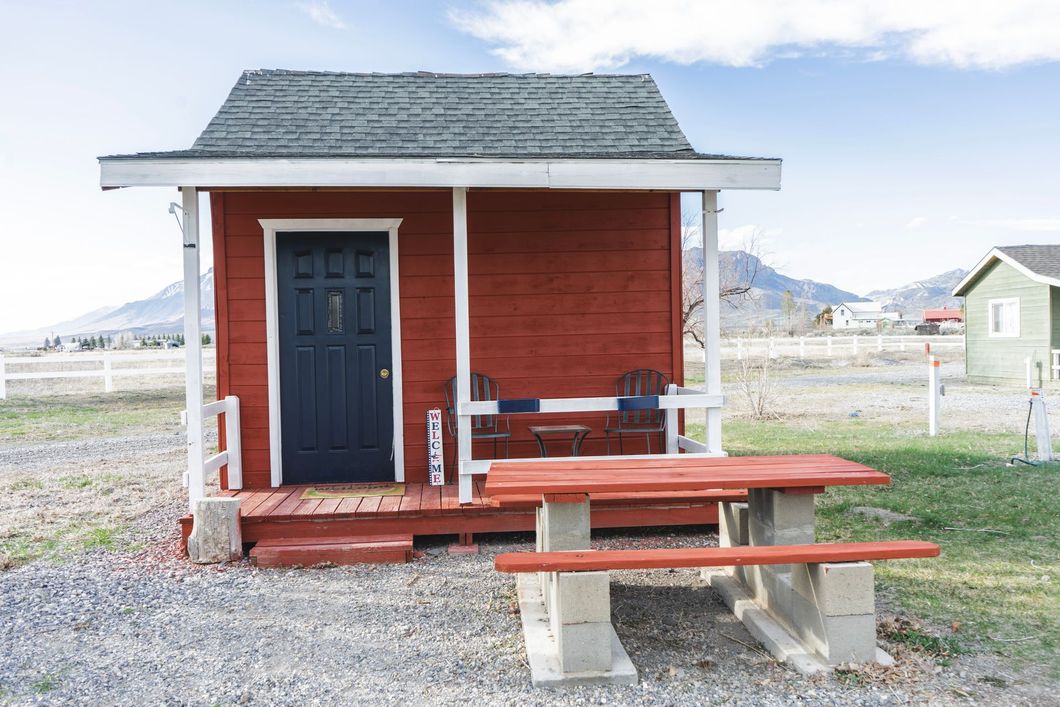 A small red shed with a porch and a picnic table.