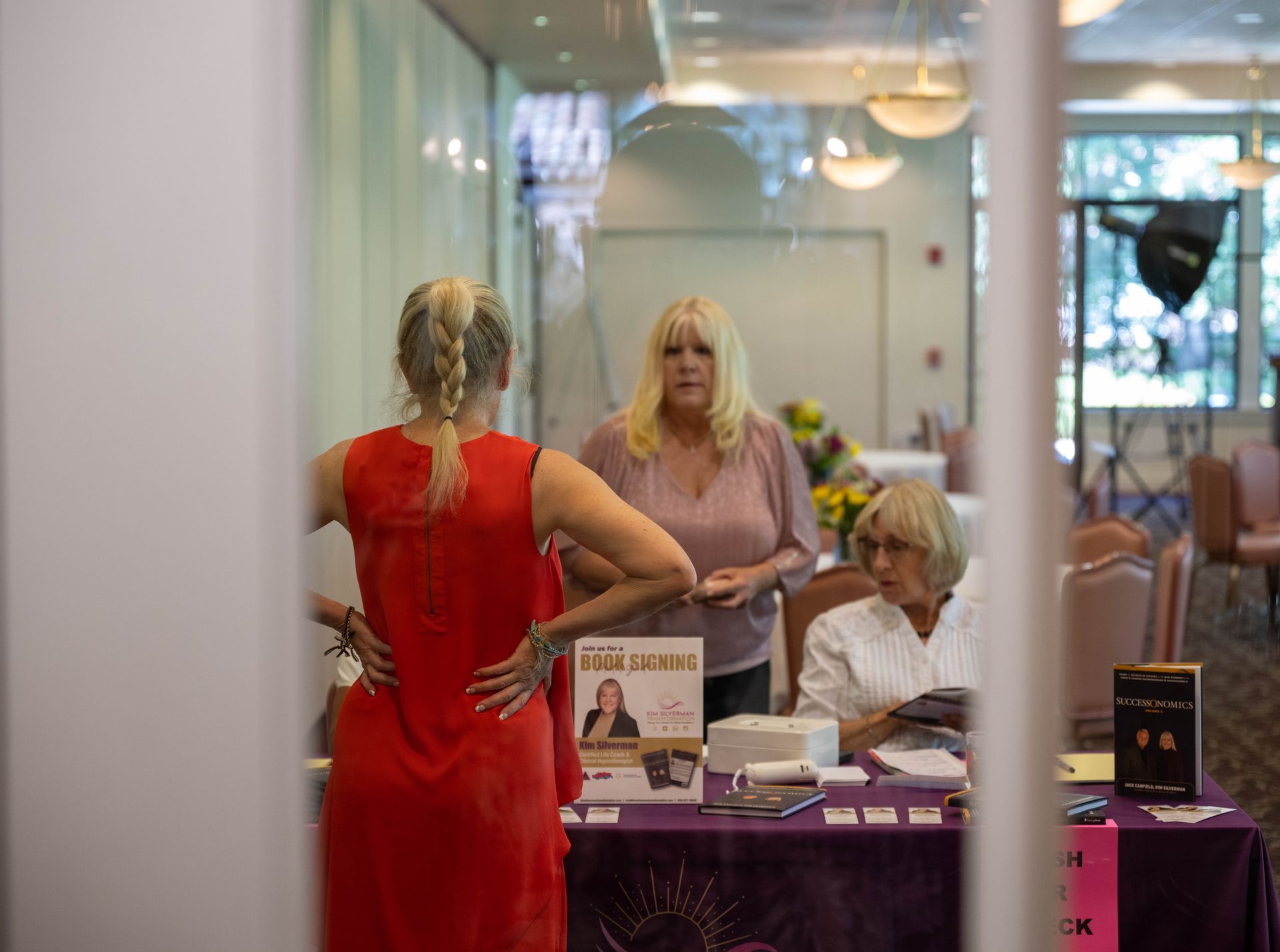 A group of women are standing around a table in a room with kim silverman.