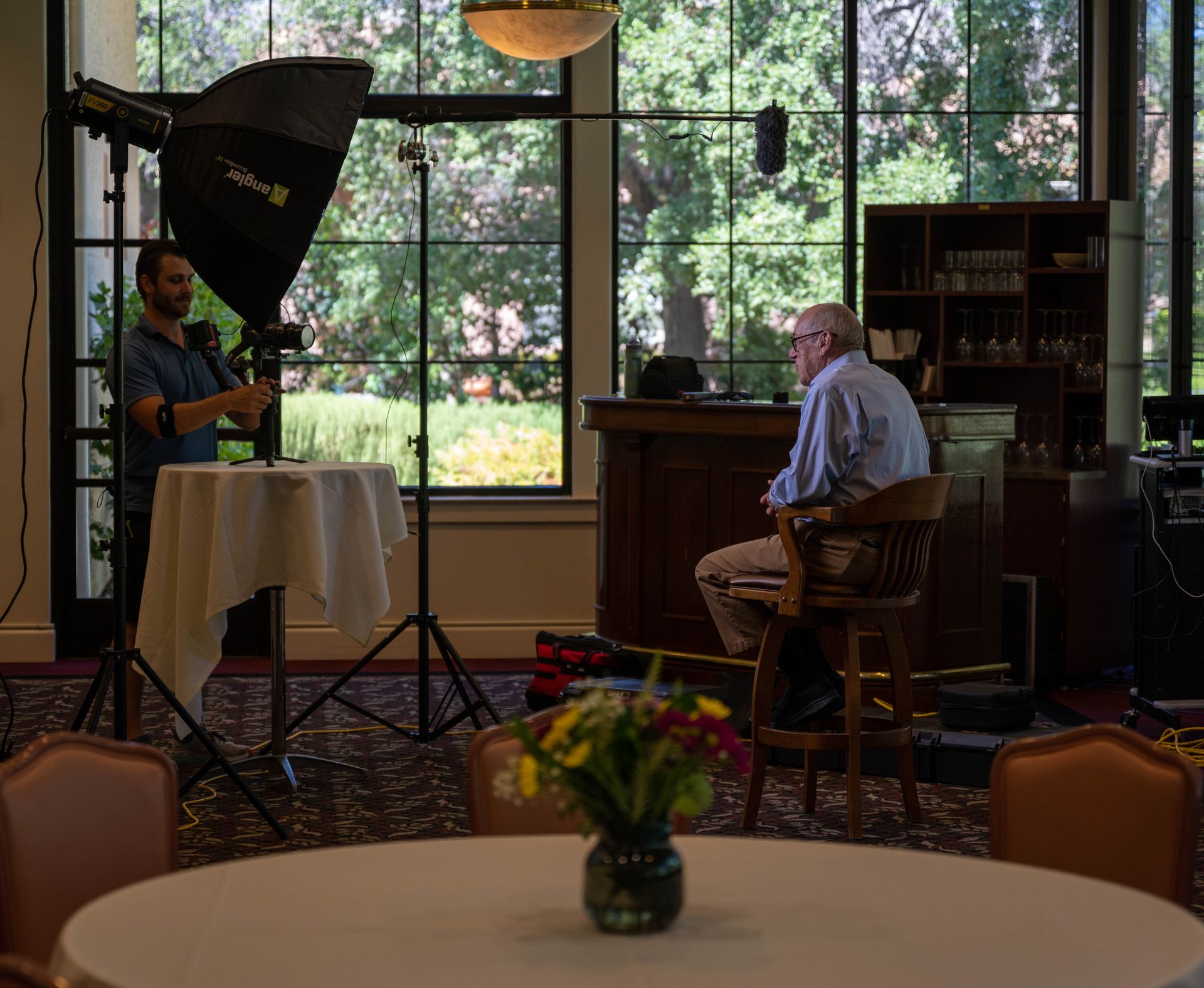 A man is sitting in a chair in front of a camera in a room.