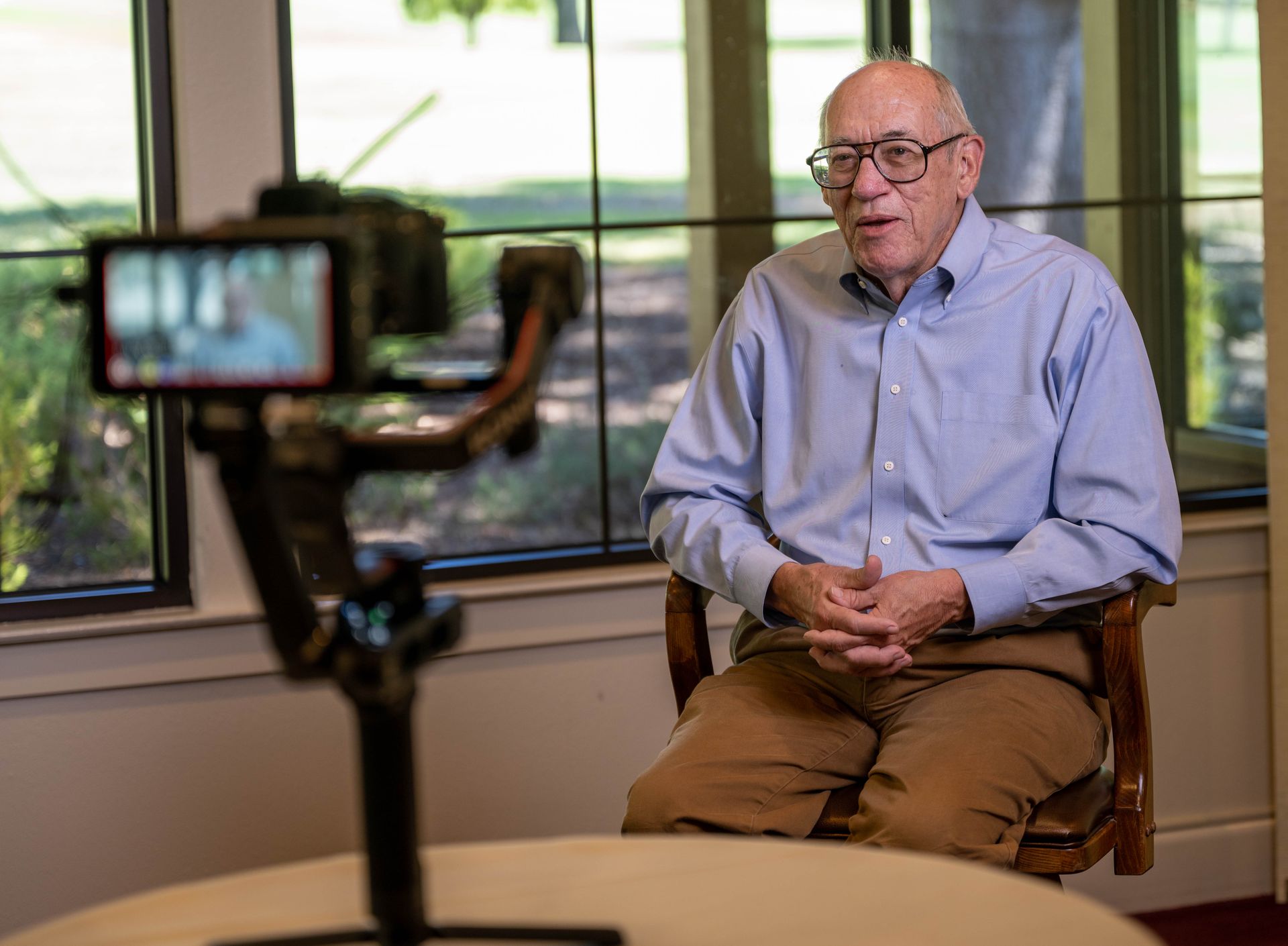 An older man is sitting in front of a camera.