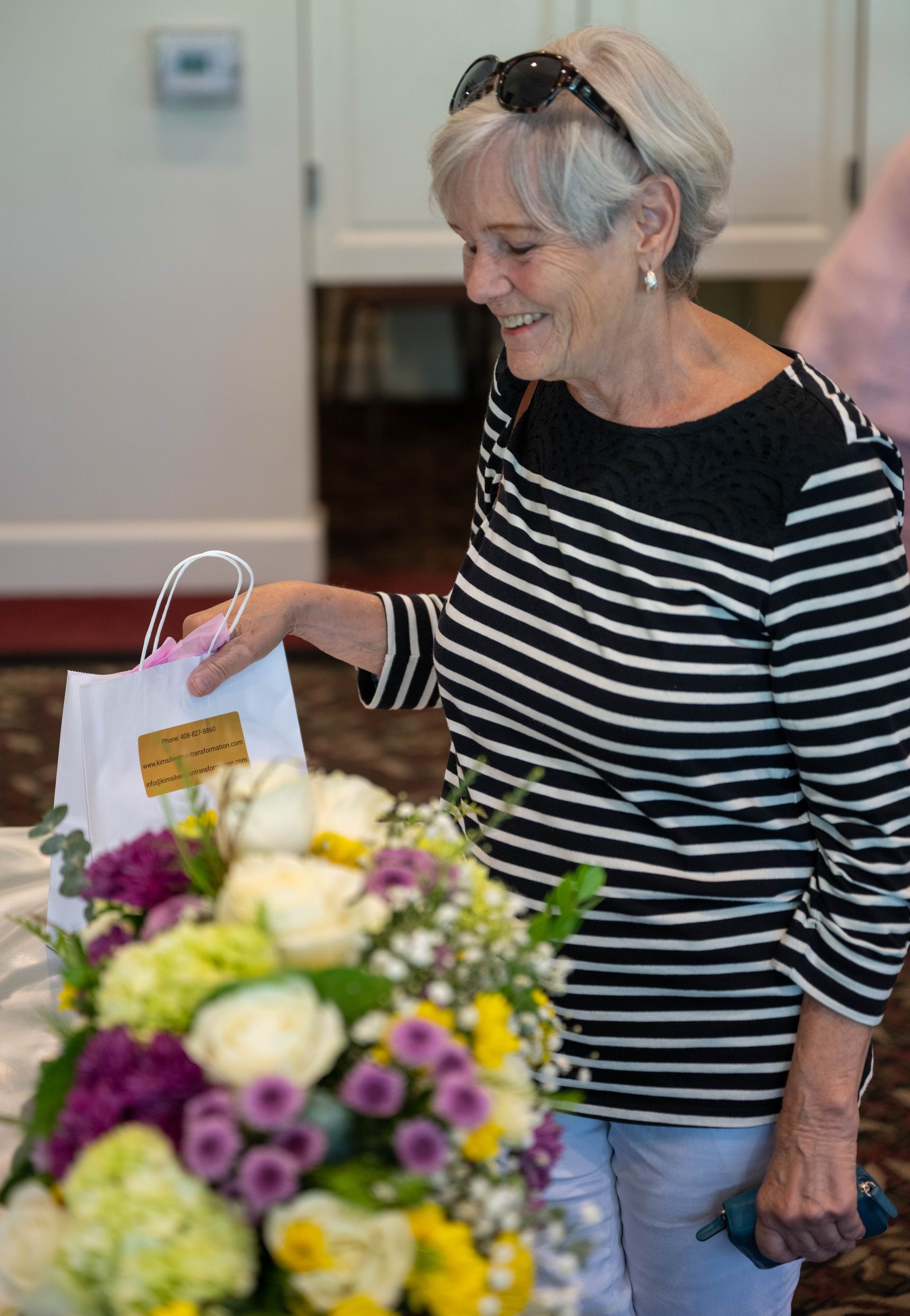 A woman in a striped shirt is holding a bag of flowers.