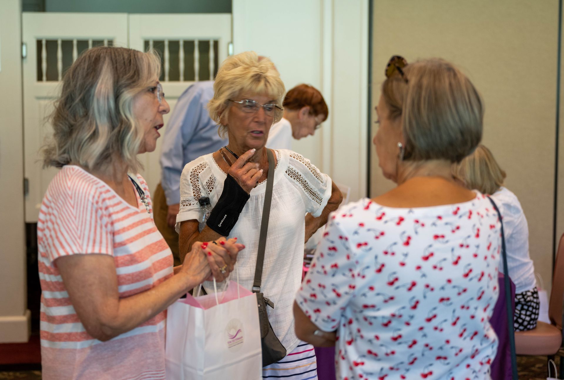 A group of women are standing in a room talking to each other.