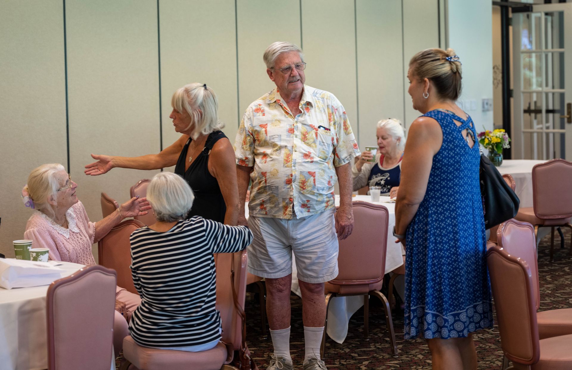 A group of people are standing in a room talking to each other.