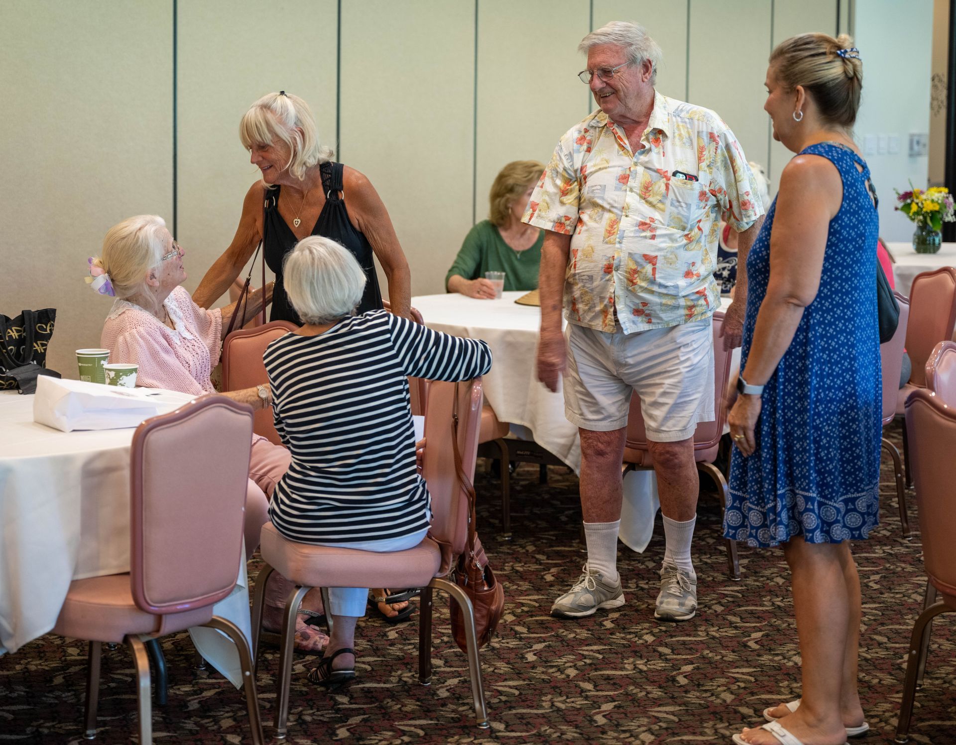 A group of people are standing in a room talking to each other.