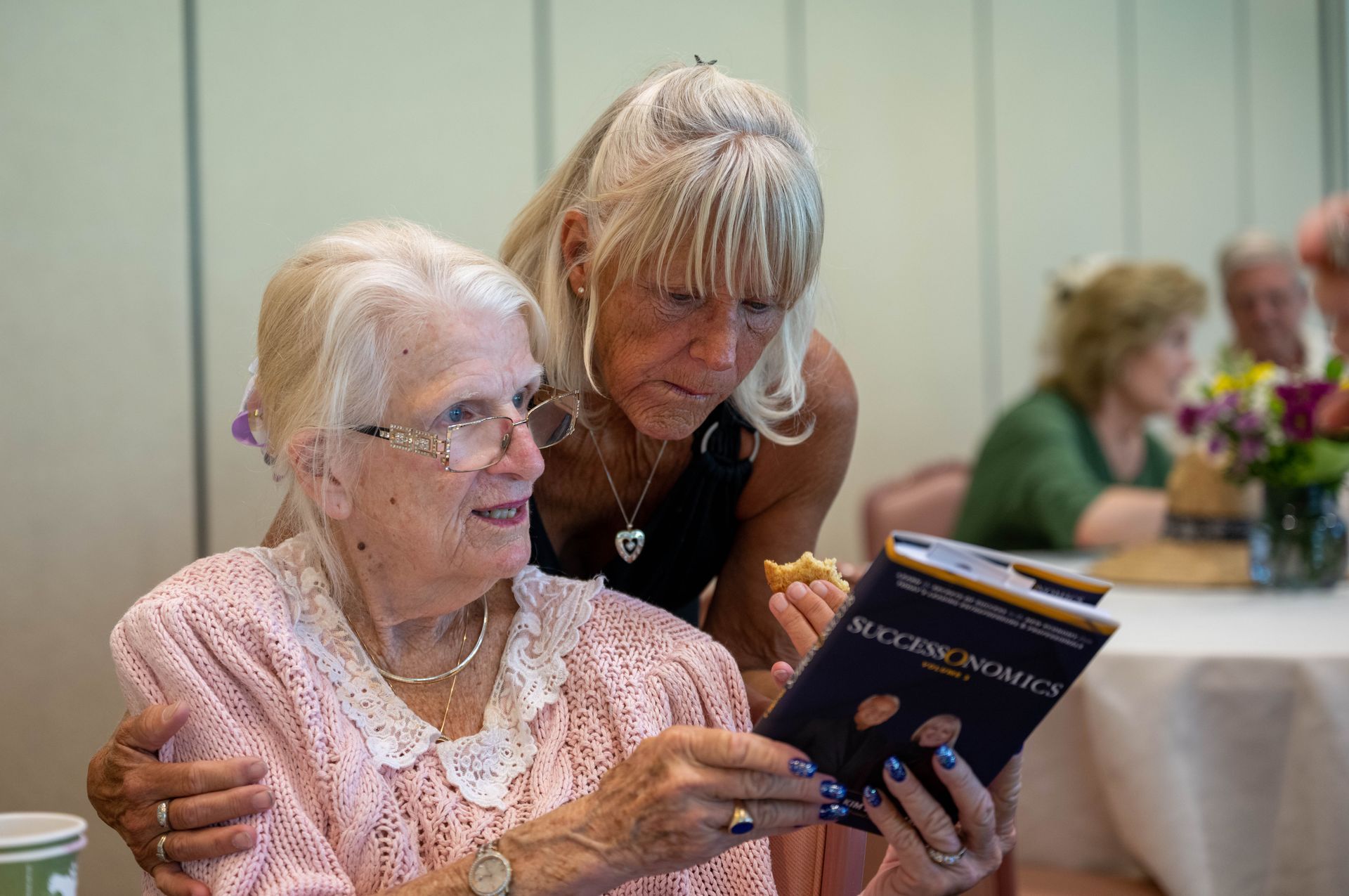 Two women are looking at a book together.