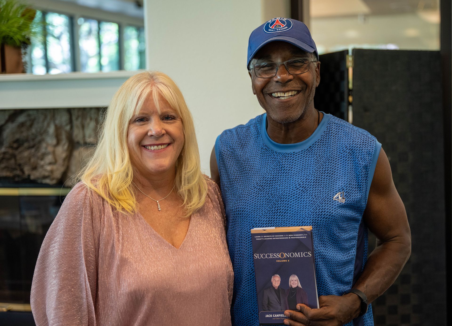 A man and Kim Silverman are posing for a picture while the man is holding a book.