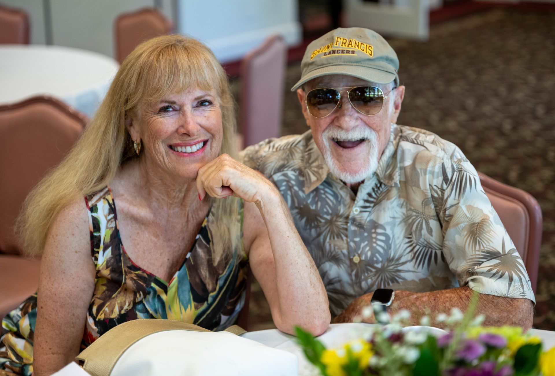 A man and a woman are sitting at a table smiling for the camera.