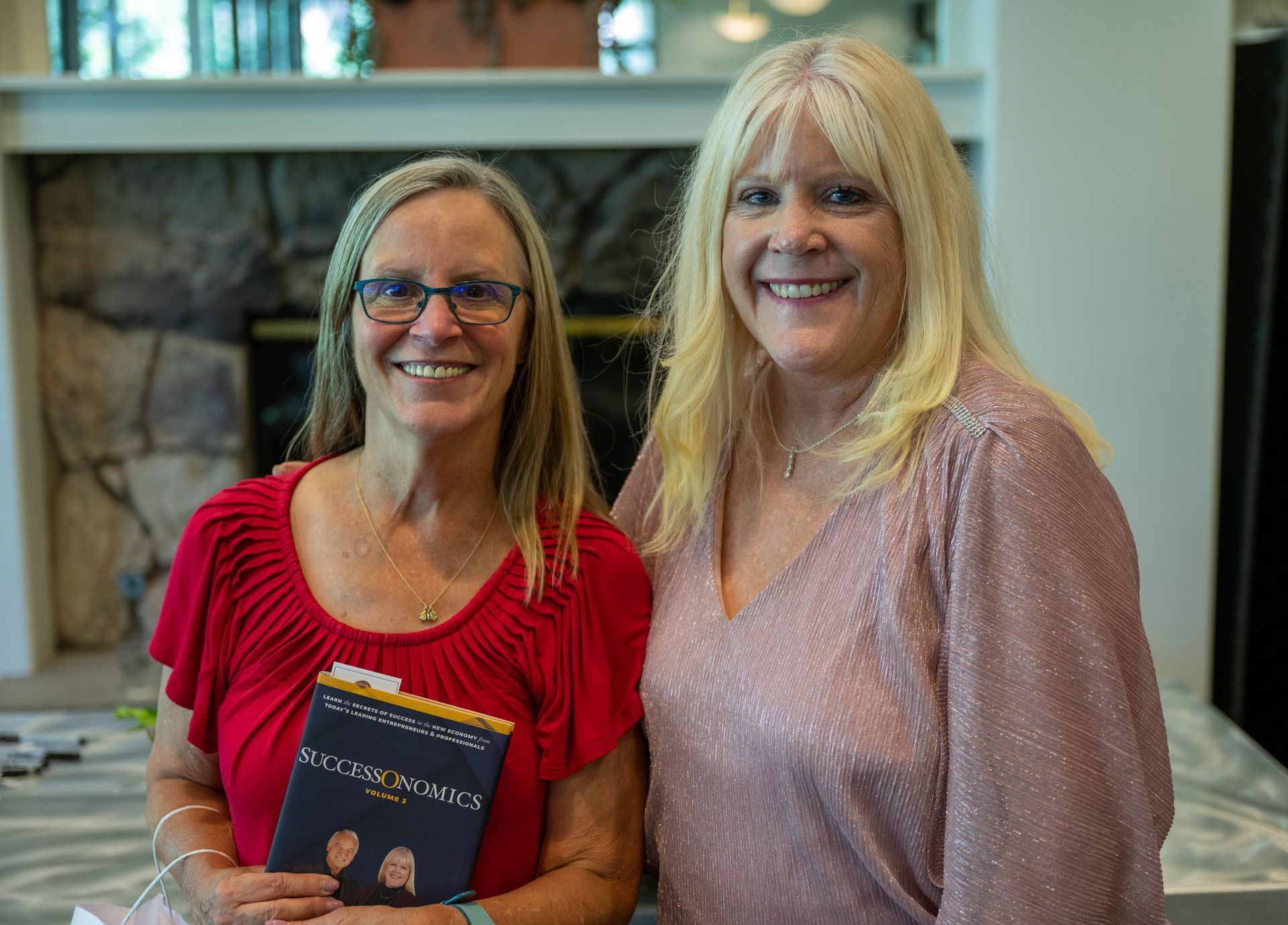 Kim Silverman and a women are posing for a picture while one of them is holding a book.