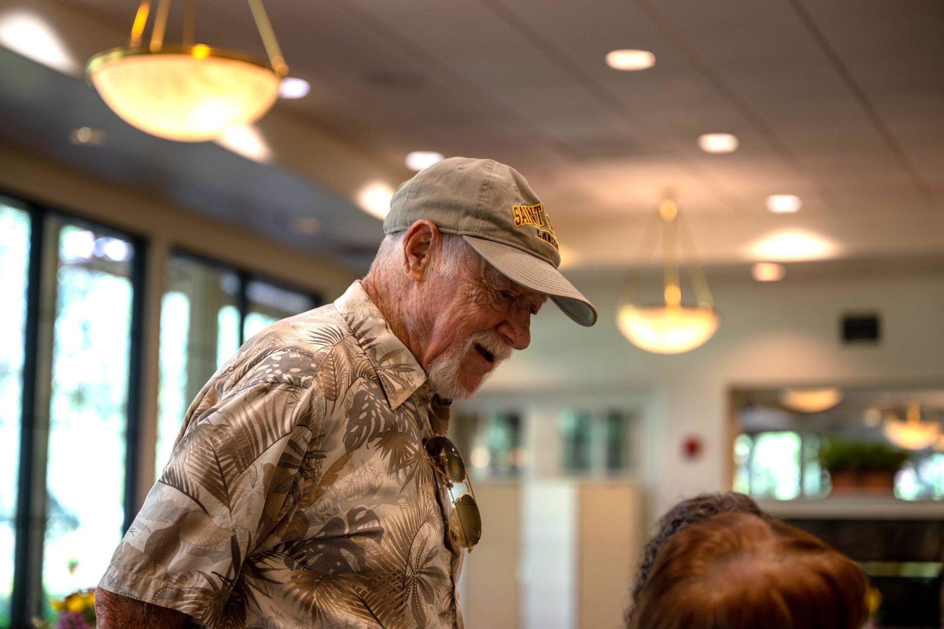 A man wearing a hat and a hawaiian shirt is standing in a room.