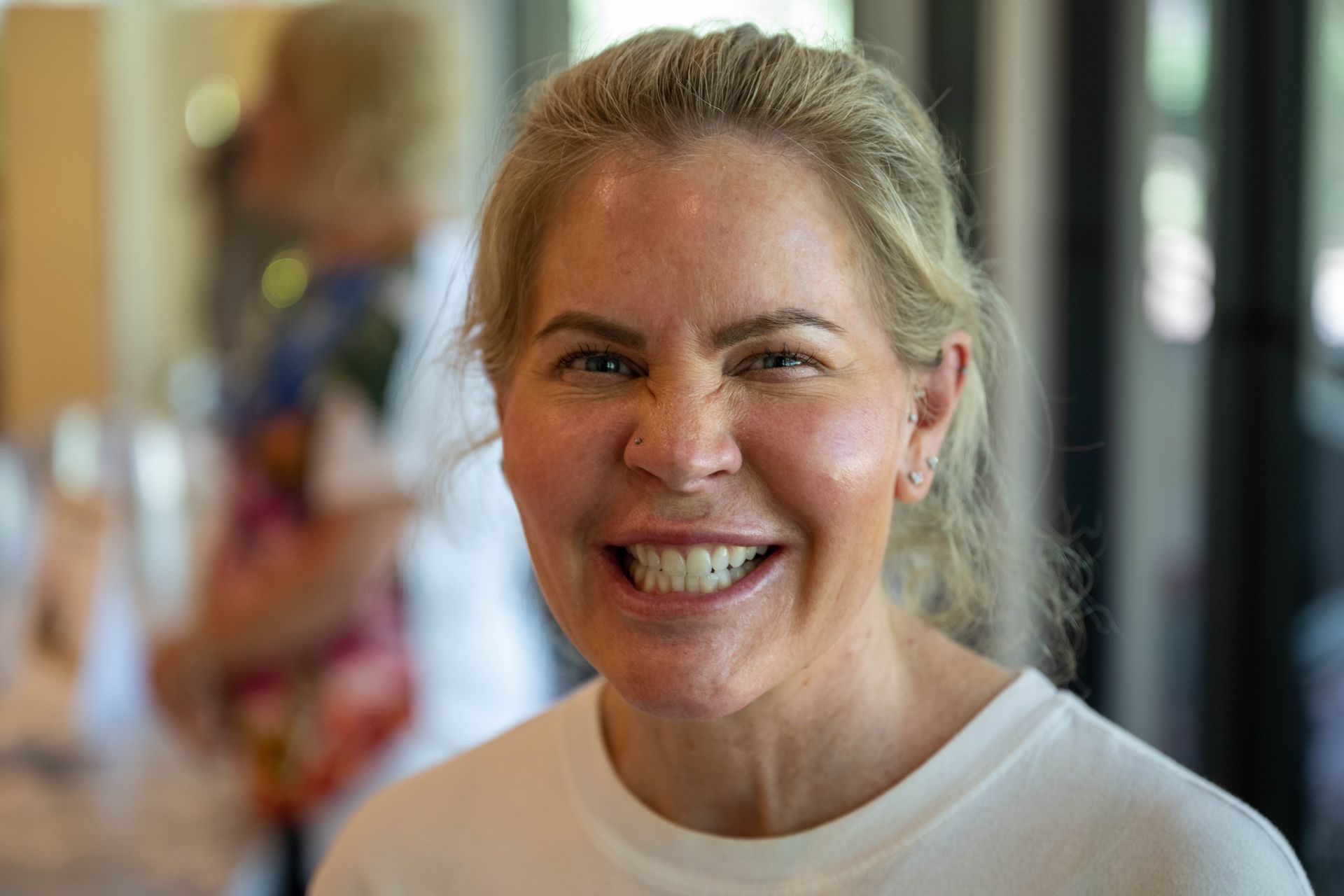 A woman is smiling for the camera while wearing a white shirt.