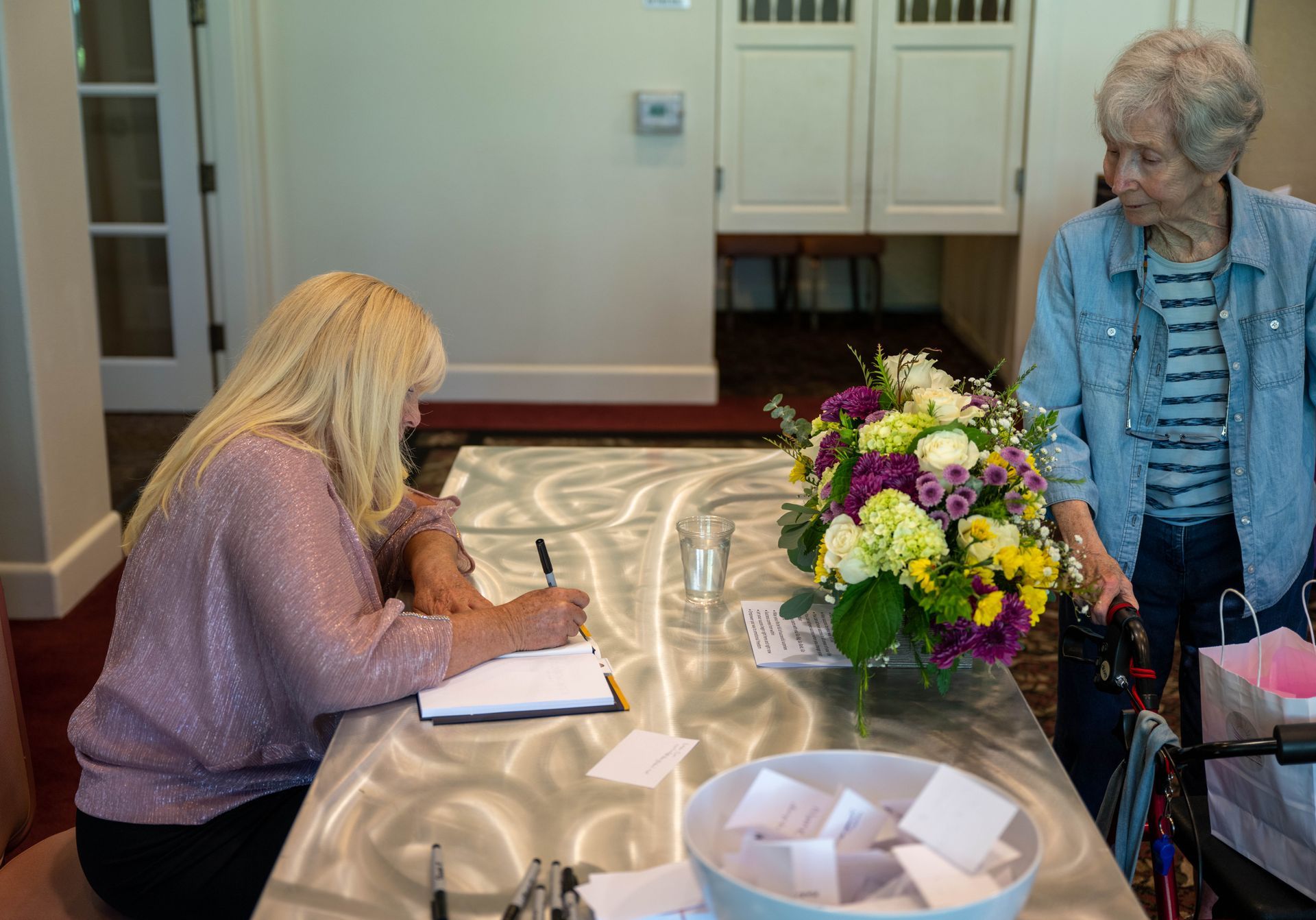 Kim Silverman with a women at a table signing SuccessOnomics book.